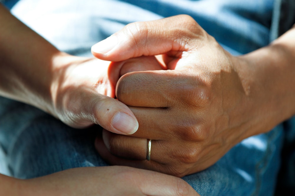 A caregiver gently holding the hands of a client